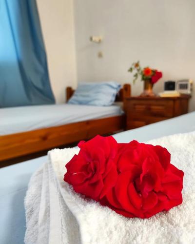 czerwona róża na białym ręczniku na łóżku w obiekcie studios.maria.anna w mieście Kamilari