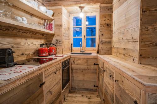 a log cabin kitchen with wooden cabinets and a window at Rascard Monterosa in Champoluc