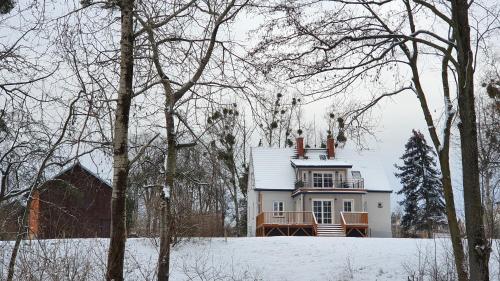 a white house in the snow with trees at Nasz Dębowiec - dom dla 15 osób, sauna, widok na staw, wielka działka in Dębowiec