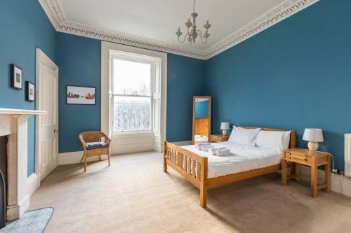 um quarto azul com uma cama e uma cadeira em Stunning 3 Bedroom Flat in Bruntsfield em Edimburgo