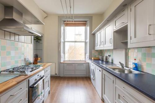 uma cozinha com armários brancos, um lavatório e uma janela em Stunning 3 Bedroom Flat in Bruntsfield em Edimburgo