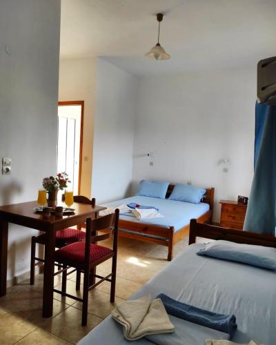 a room with two beds and a table and a bed at studios.maria.anna in Kamilari