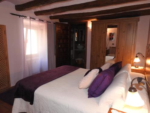 a bedroom with a bed with purple and white pillows at El Molí de Pontons suites con jacuzzi spa in Pontons