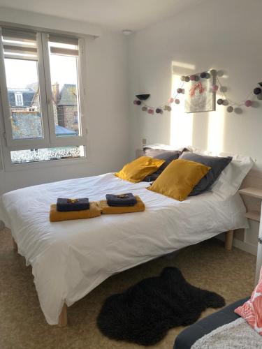 Un dormitorio con una gran cama blanca con almohadas amarillas. en Studio cocooning, en Saint-Malo