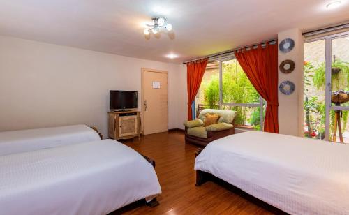 a bedroom with two beds and a tv and a chair at Hotel Boutique Los Balcones in Cuenca