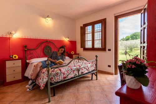 una donna seduta su un letto in una camera da letto di Agriturismo La Banchella a Scarlino