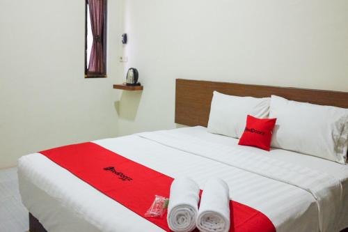 ein Bett mit roten und weißen Handtüchern darauf in der Unterkunft RedDoorz Syariah near Exit Tol Pemalang Comal 2 in Comal