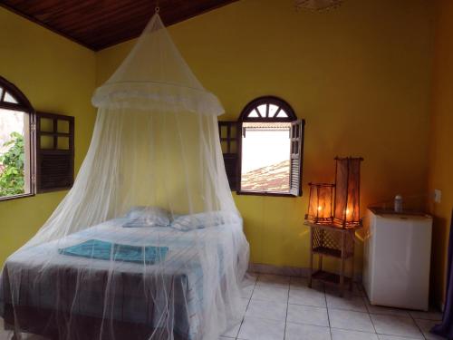 a bedroom with a bed with a mosquito net at Suite d'Artistes in Imbassai