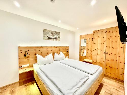 sypialnia z dużym łóżkiem i drewnianą ścianą w obiekcie Royal Swan Appartement, Tirol w mieście Fügen