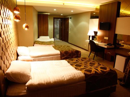 a hotel room with three beds and a desk at Feyzan Hotel in Corum