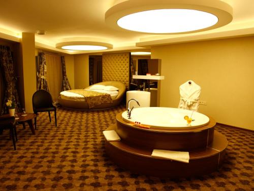 a hotel room with a tub and a bed at Feyzan Hotel in Corum