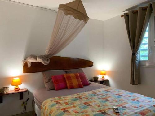 a bedroom with a bed with a canopy and two lamps at La villa ô plaisir in Deshaies