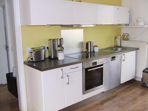 a small kitchen with white cabinets and a sink at Ferienwohnung Hochwald - im Herzen des Saarlandes in Quierschied
