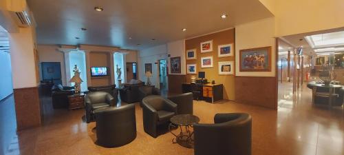 a lobby with a waiting room with chairs and tables at Jandaia Hotel Campo Grande in Campo Grande
