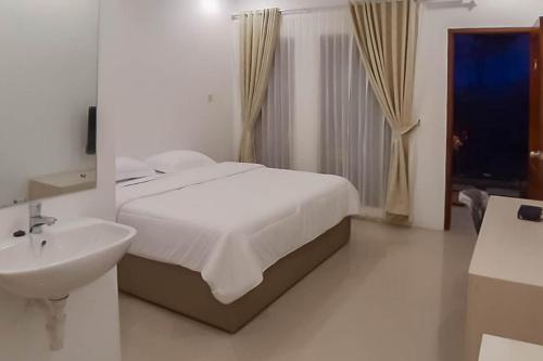 a white bedroom with a bed and a sink at RedDoorz near Pantai Madasari Pangandaran in Bulakbenda