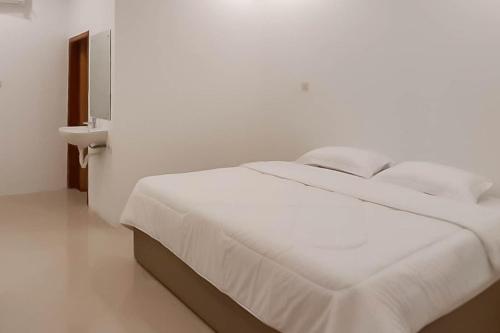 - un lit blanc dans une chambre blanche avec un mur blanc dans l'établissement RedDoorz near Pantai Madasari Pangandaran, à Bulakbenda