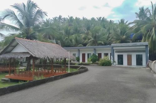 a building with chairs and palm trees in the background at RedDoorz near Pantai Madasari Pangandaran in Bulakbenda