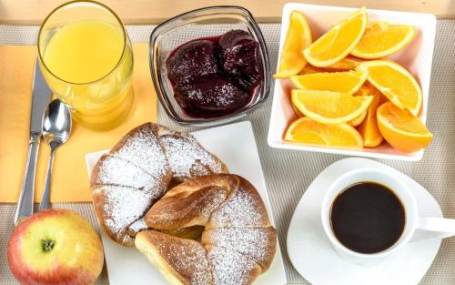 a table with a plate of bread and oranges and a cup of coffee at The Stone Forest in Kalabaka