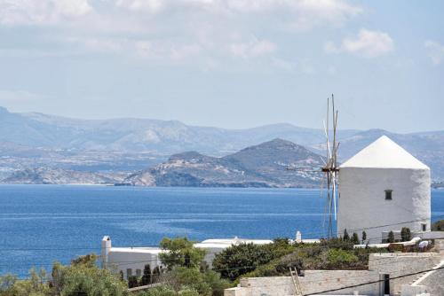een witte windmolen op een heuvel naast een waterlichaam bij Traditional Villa 5-min walk to the beach in Santa Maria