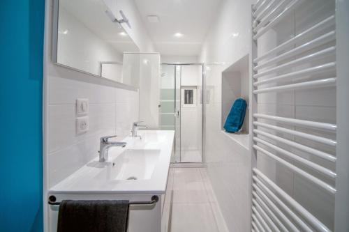 a white bathroom with two sinks and a mirror at Appartement Contemporain au coeur du centre ville in Mâcon