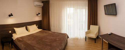 um quarto com uma cama, uma cadeira e uma janela em Colinele Aurii Cimislia em Cimişlia