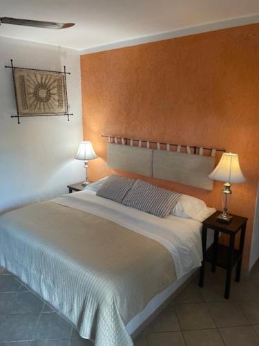 a bedroom with a bed and two lamps on tables at Villa Escondida Guest House Cozumel Downtown in Cozumel