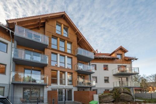 an apartment building with a wooden facade and balconies at StoneHill24 - Apartament & Spa in Szklarska Poręba