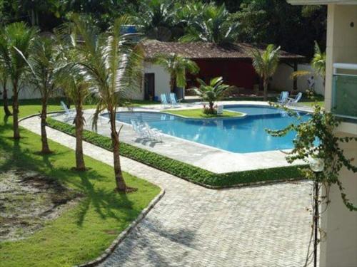 una piscina con palmeras junto a una casa en Casa de praia em condomínio fechado Juquei en São Sebastião