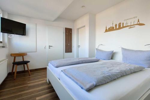 Cette chambre comprend un lit avec des draps bleus et une télévision à écran plat. dans l'établissement Ferienwohnung-416-mit-eigenem-Whirlpool-Residenz-Hohe-Lith-Duhnen, à Cuxhaven