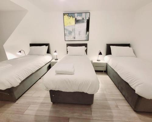 a room with two beds with white sheets and lamps at Garland Modern 2 Bedroom Apartment With Parking London in Plumstead
