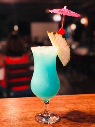 a blue drink sitting on a table with an umbrella at Gran Lençóis Flat Apartamento in Barreirinhas