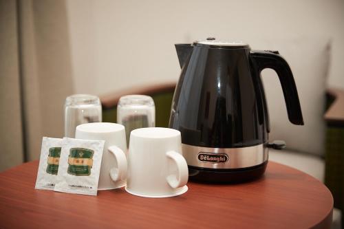 a coffee pot and cups on a table at THE GRAND HOTEL GINOWAN in Ginowan