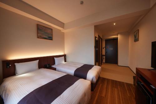 a hotel room with two beds and a television at THE GRAND HOTEL GINOWAN in Ginowan