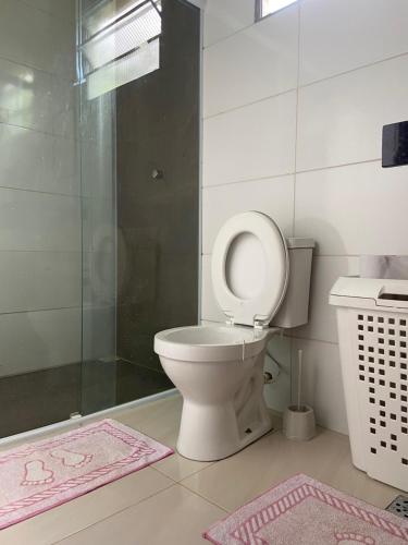 a bathroom with a toilet and a shower and a pink rug at Casa em Paraty, piscina com vista para o mar in Paraty