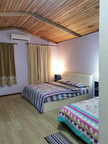 1 dormitorio con 2 camas y techo de madera en Cassava Homestay - Rumah Santai, en Kampong Lamanak
