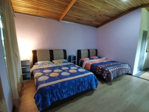 1 dormitorio con 2 camas y techo de madera en Cassava Homestay - Rumah Santai, en Kampong Lamanak