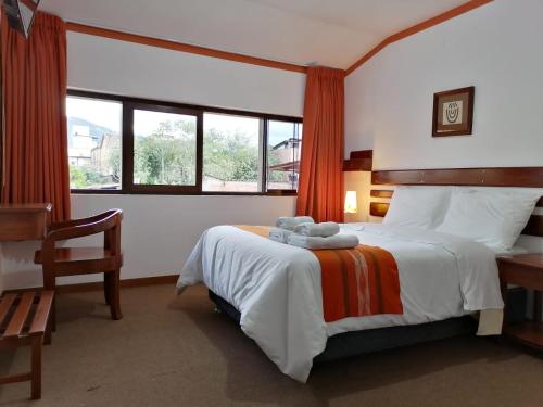 a bedroom with a bed and a chair and windows at Explorer Deluxe Hotel in Chachapoyas