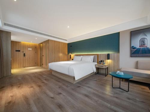 a bedroom with a large white bed and a couch at 银座佳悦精选（菏泽郓城水浒城店） in Yuncheng