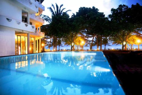 a large blue swimming pool in front of a building at Oasey Beach Hotel in Bentota