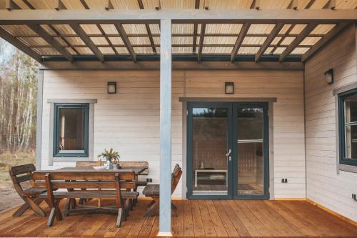 a patio with a table and benches on a wooden deck at sosnowelowe in Lamkowo