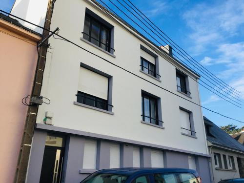 een wit gebouw met zwarte ramen op een straat bij Grand Studio avec terrasse proche de l'hypercentre de Lorient in Lorient