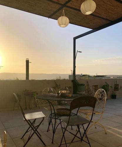 a table and chairs on a patio with the sunset at יעלת חן Ya'alat hen in Yeroẖam