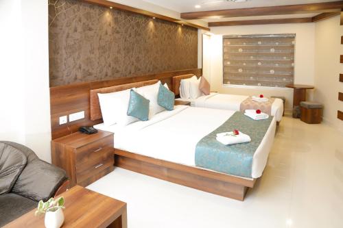 ein Hotelzimmer mit 2 Betten und einem Sofa in der Unterkunft Hotel Crystals Cove in Thekkady