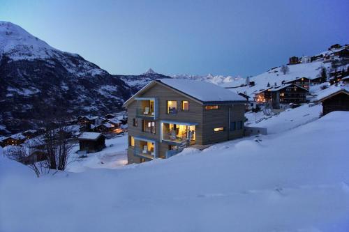 una casa en la nieve con luces encendidas en Sera Lodge, en Grächen