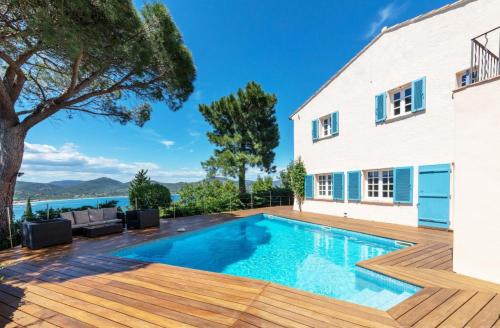 a swimming pool with a wooden deck and a house at Villa with Magic view of Bay of Saint Tropez in Saint-Tropez