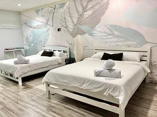 a bedroom with two beds and a mural of leaves at The Nook, Kuala Terengganu in Kuala Terengganu