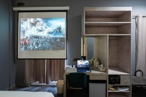 a bedroom with a bed and a desk with a laptop at Rest Chinatown Hotel in Singapore