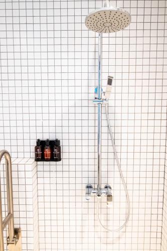 a shower in a white tiled bathroom at Rest Chinatown Hotel in Singapore