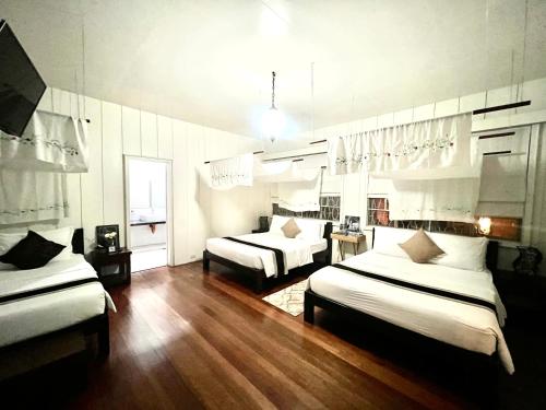 a room with two beds in a room with wooden floors at La Casa Bianca in Baguio