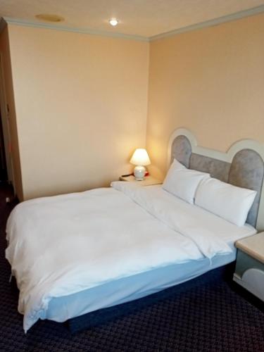 a hotel room with a large white bed and a lamp at Chungli Business Hotel in Zhongli